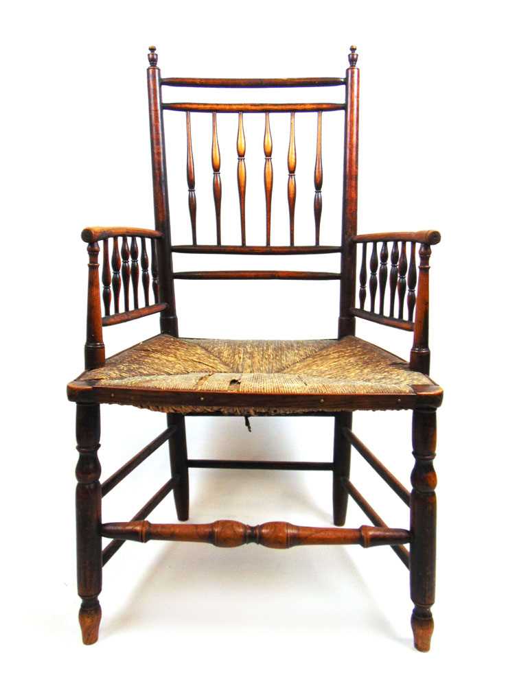 An early 19th century ash arm chair, the spindle back and arms over a rush seat on turned legs and