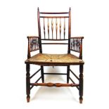 An early 19th century ash arm chair, the spindle back and arms over a rush seat on turned legs and