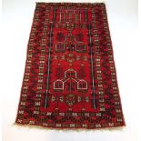 A handwoven Afghan prayer rug, the serrated leaf border surrounding a red ground geometric field,