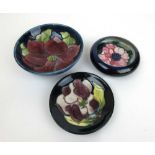 A Moorcroft Clematis pattern bowl together an Anemone pattern ashtray and one other Moorcroft pin