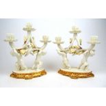 A pair of Moore Bros. three branch candelabra, the candle bearing putti on gilt edged base, h. 33