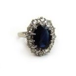 An 18ct white gold, sapphire and diamond cluster ring. The central oval cut blue sapphire assessed