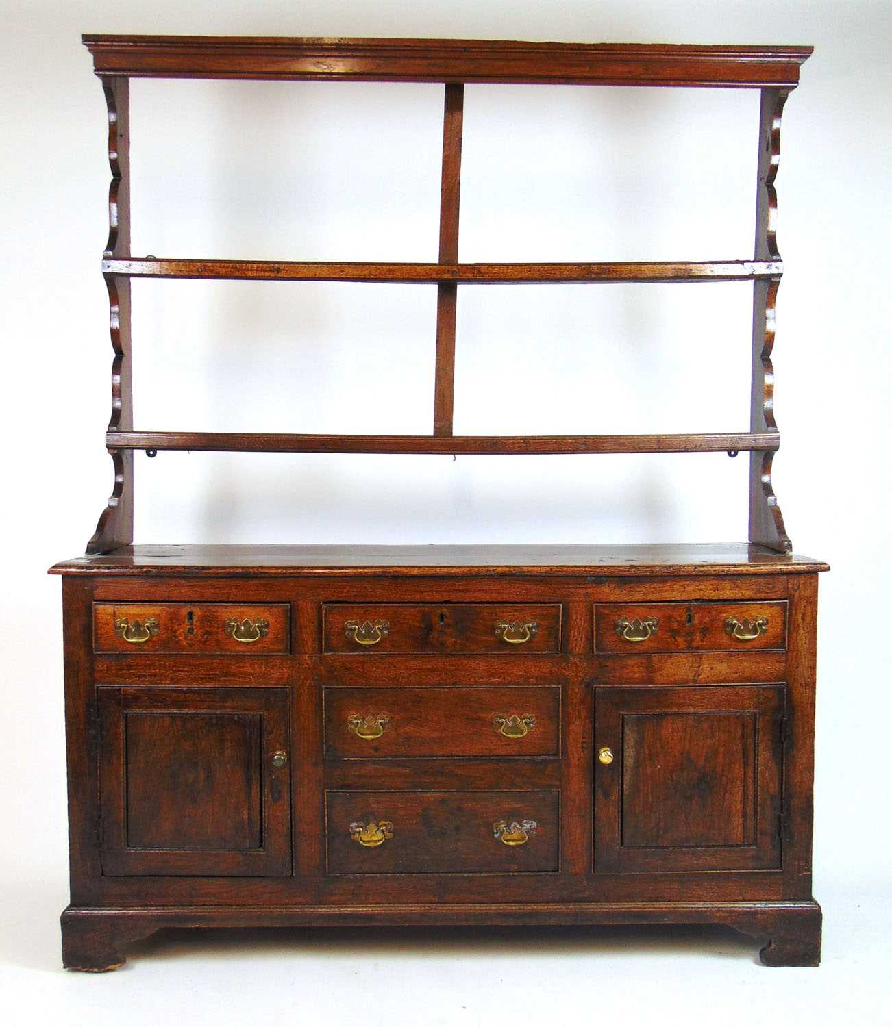 An 18th century oak dresser, the plate rack over the base with drawers and cupboard doors on bracket