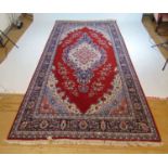 A handwoven Persian rug, the multi line border surrounding a red ground field with three