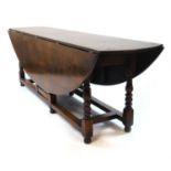 A 20th century, 18th century style oak dining/wake table, the drop leaf top supported on single gate