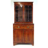 An early 19th century mahogany bookcase, the top with two glazed doors over single drawer and two