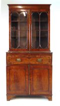 An early 19th century mahogany bookcase, the top with two glazed doors over single drawer and two
