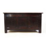 An early 18th century oak coffer, the four panel top lifting to reveal a vacant interior over a