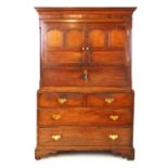 An 18th century oak cabinet on chest, the dental cavetto cornice over an inlaid entablature with