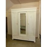 An early 20th century painted French three door wardrobe with two drawers to base