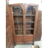 An early 20th century oak display cabinet having a pair of leaded glazed doors