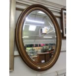 An ornate gilt framed oval bevel glass mirror