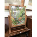 An early 20th century oak framed swivel action fire screen having an embroidery under glass