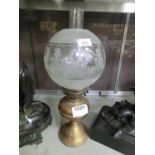 A brass columned oil lamp with spherical etched glass shade
