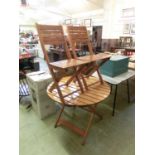 A slatted folding garden table with a pair of matching folding chairs