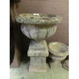 A composite stone garden urn on pedestal