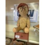 An early 20th century teddy bear with a scratch built rocking chair containing an assortment of