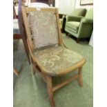 An early 20th century beech nursing chair having a cut draylon fabric to seat and back