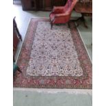A middle eastern cream ground rug with red border measuring 303x209cm