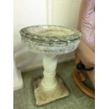 A weathered stoneware birdbath