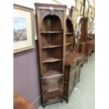 A mid-20th century carved oak full height corner cabinet having open storage above carved panel