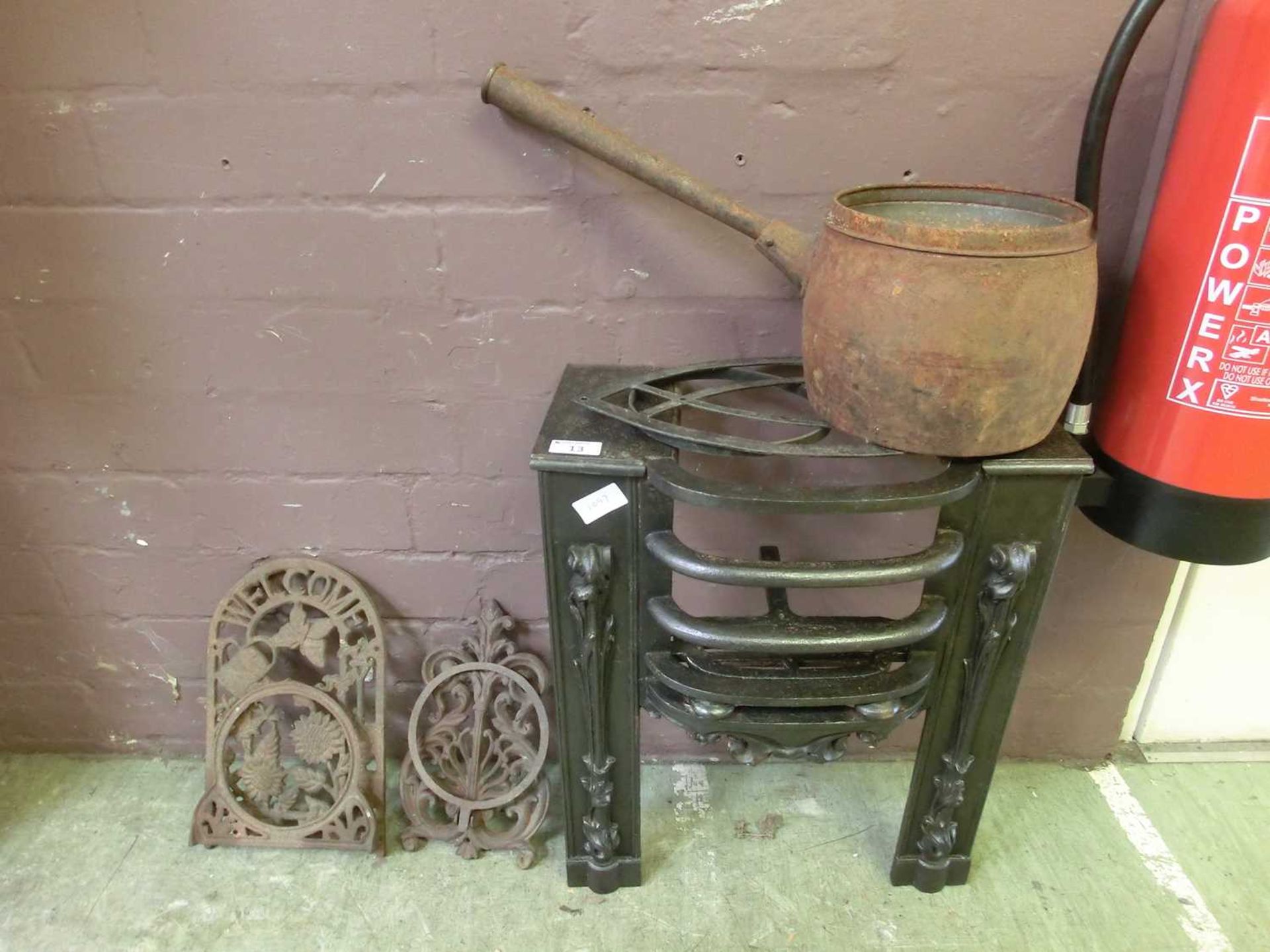 A cast iron fire grate along with a pot and two brackets