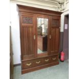 An early 20th century walnut two door wardrobe, central bevelled mirror flanked by cupboard doors