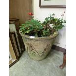 A terracotta plant pot with geraniums and a glazed pot