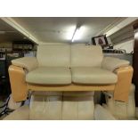 An Ekornes/Stressless beech framed two seat sofa upholstered in a cream leatherette fabric