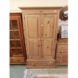 A modern pine two door wardrobe with drawer to base