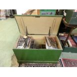 A green wooden tool box containing a large selection of hand tools