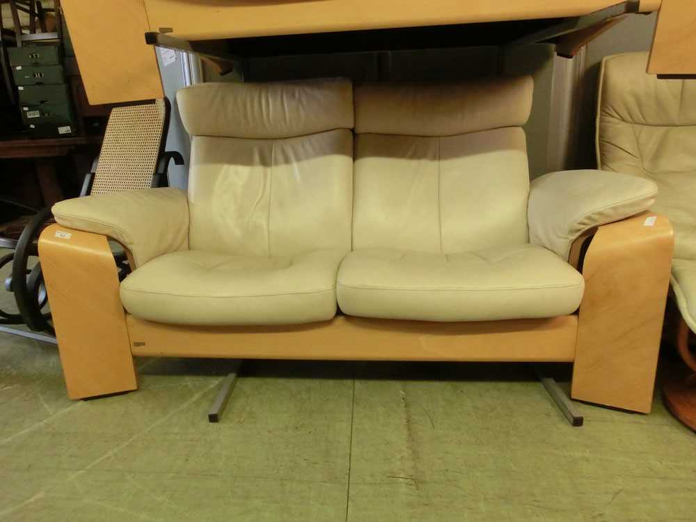 An Ekornes/Stressless beech framed two seat sofa upholstered in a cream leatherette fabric