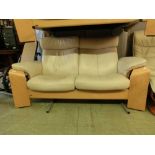 An Ekornes/Stressless beech framed two seat sofa upholstered in a cream leatherette fabric