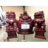 A red moulded model of Buddha along with two similar moulded models of foo dogs