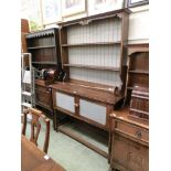 A mid-20th century oak dresser having plate rack to top, the base having two cupboard doors