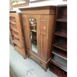 An Edwardian oak wardrobe having a mirrored centre door with drawer to base