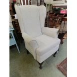 A modern white gold upholstered wing back aremchair