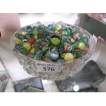 A cut glass bowl containing a large quantity of marbles