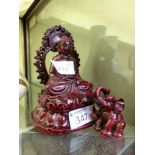 A red moulded Indian buddha figurine along with a similar small elephant