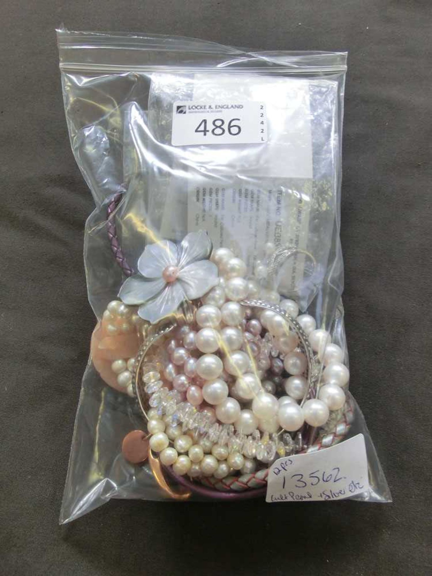 A bag containing an assortment of pearl necklaces, silver items, etc