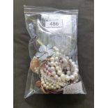 A bag containing an assortment of pearl necklaces, silver items, etc