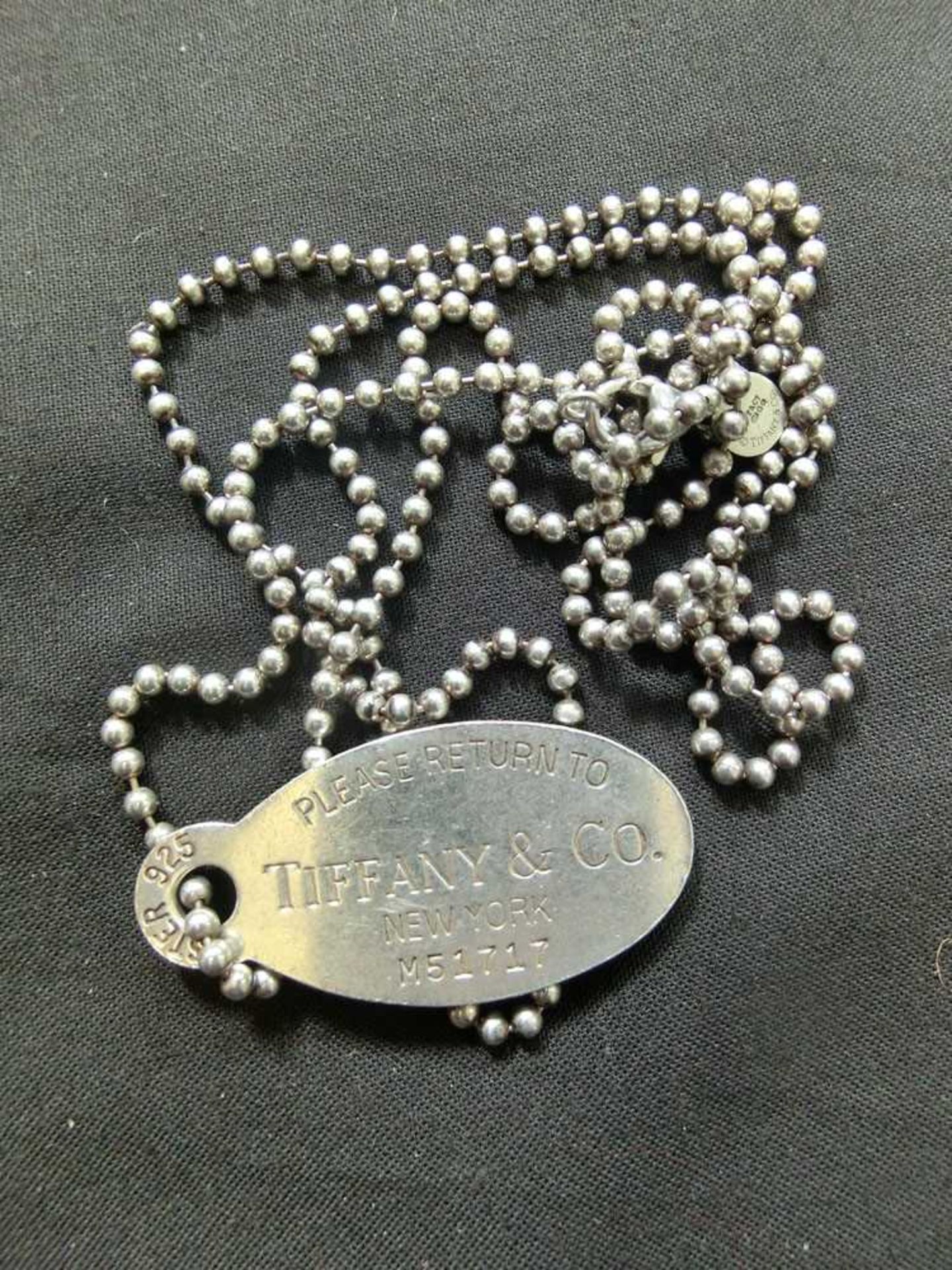 A white metal Tiffany and Co tag, marked 'Sterling 925' on beaded chain