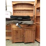 A modern pine dresser having plate rack above the base having two drawers above cupboard doors