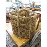 A large wicker log basket containing a quantity of wooden logs