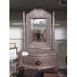 An embossed metal dressing table mirror with trinket drawer to base