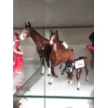 Two brown Beswick horses along with a matching foal