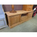 A waxed pine dresser base having open storage above single drawer flanked by cupboard doors