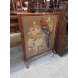 An early 20th century rosewood inlaid fire screen having a needlework of parrot under glass