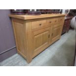 A modern oak dresser base having three drawers above a pair of cupboard doors