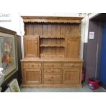 A substantial waxed pine dresser, the top with three centre drawers and open storage flanked by